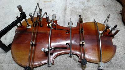 This violin had fallen at least twice and was riddled with cracks. Seen here are the various clamps I use to bring the wood back together as the glue dries. 